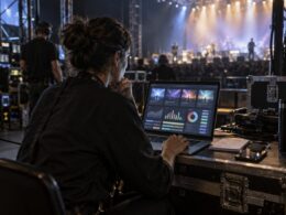 Promotora consulta las ventas de varios eventos desde un portátil junto al escenario